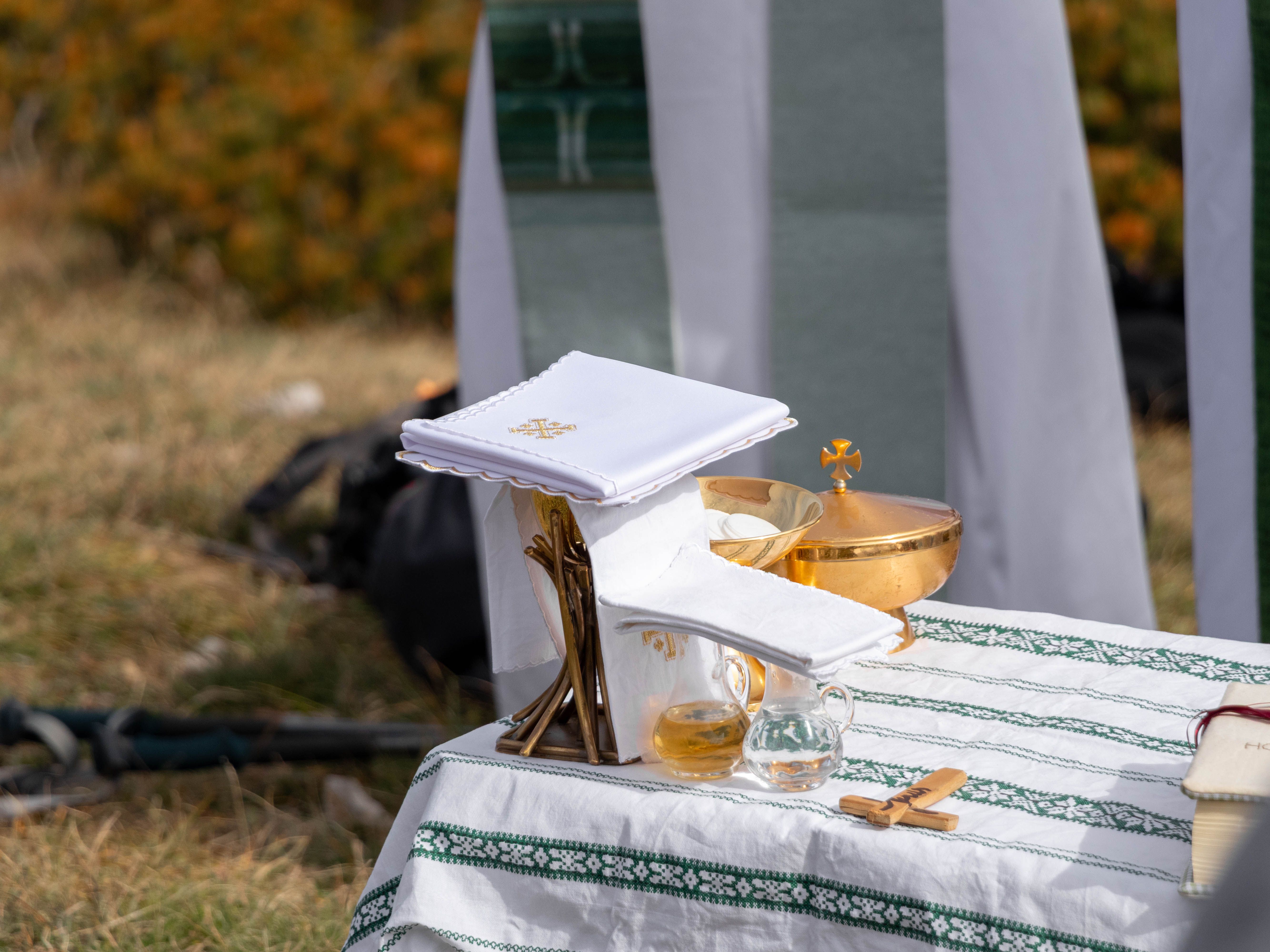 An outdoor altar setup for a religious ceremony with communion elements on a table.