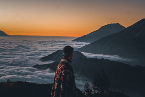 在日落时站在山顶上的男人