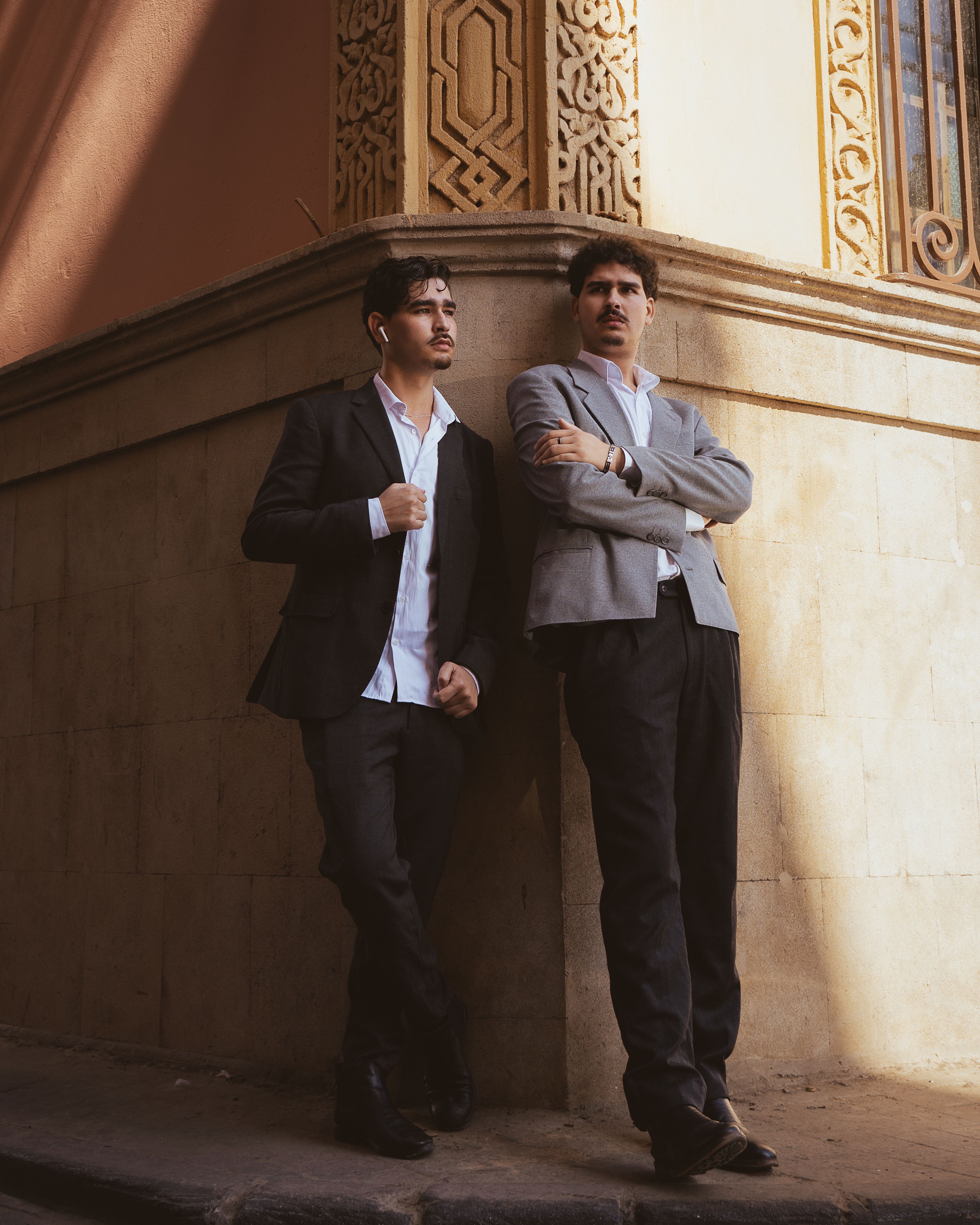 Two men in formal attire posing against architectural background in Casablanca.