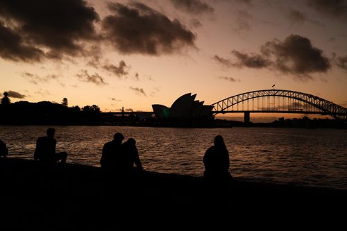 Free Silhouetted view of people and iconic Sydney landmarks at sunset. Stock Photo