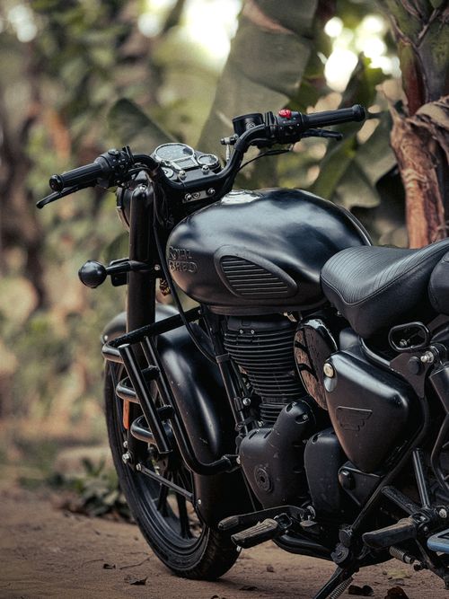 Free A sleek black motorcycle parked outdoors against a lush green backdrop, perfect for adventure enthusiasts. Stock Photo