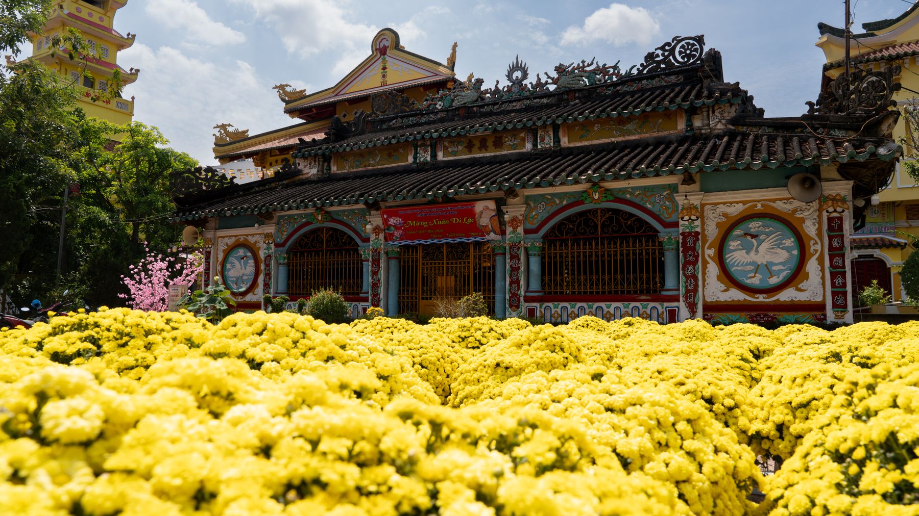 Ein wunderschöner Tempel in Vietnam, umgeben von leuchtend gelben Blumen unter einem sonnigen Himmel.