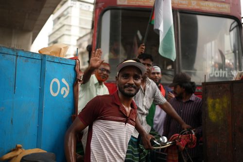Free A smiling man poses next to a vibrant city bus in Dhaka, capturing the lively street atmosphere of Bangladesh. Stock Photo