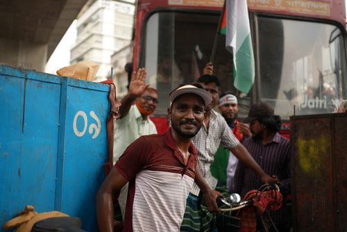 Free A cheerful cyclist poses in a lively street scene in Dhaka, Bangladesh, near a red bus. Stock Photo