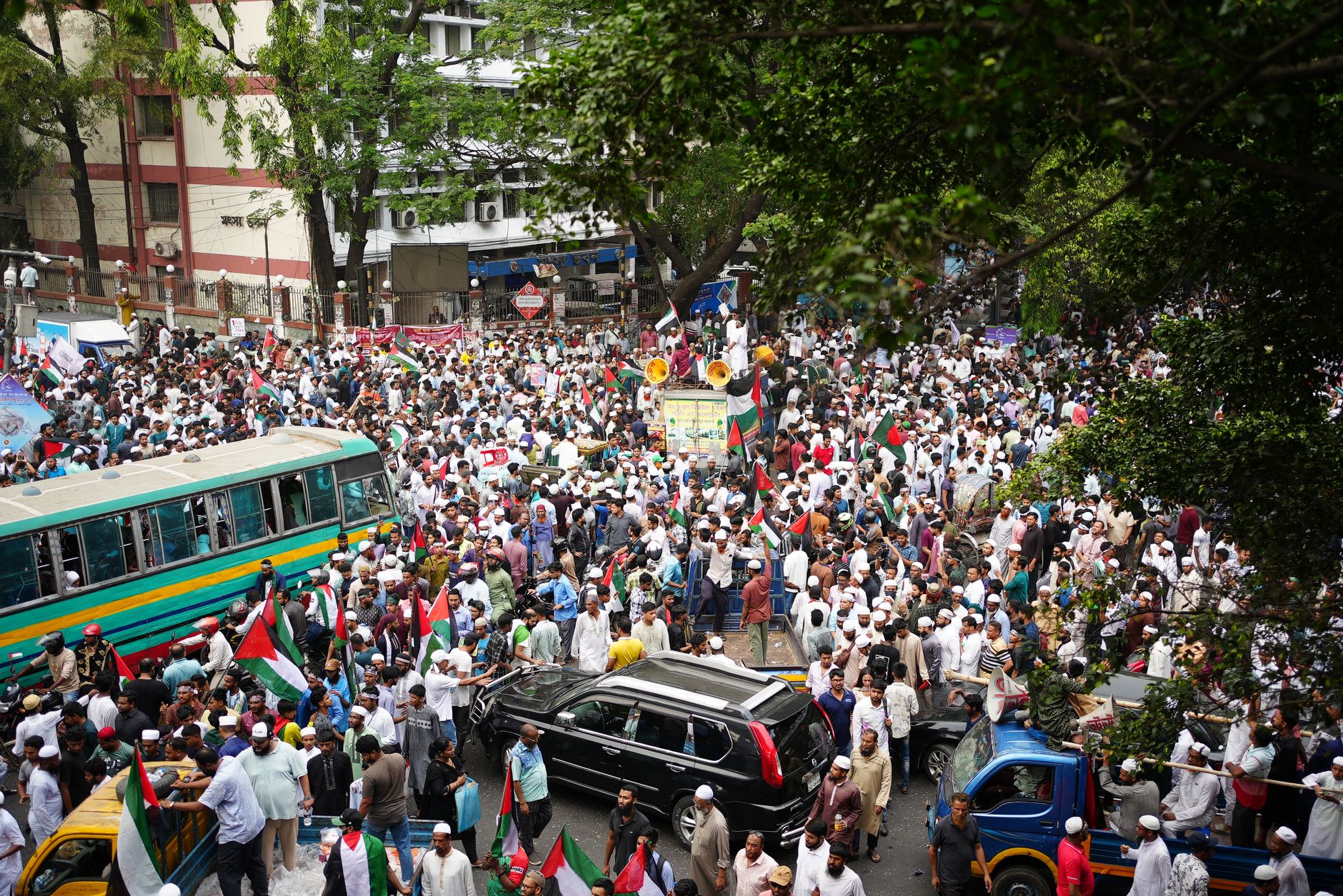 A large crowd of protestors gathering with flags in Dhaka, Bangladesh.