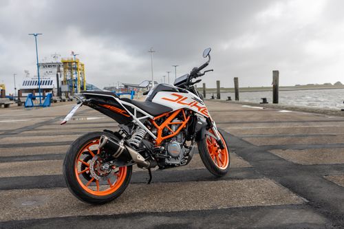 Free A vibrant KTM Duke motorcycle parked at the picturesque Dagebüll harbor in Germany, showcasing its striking design. Stock Photo
