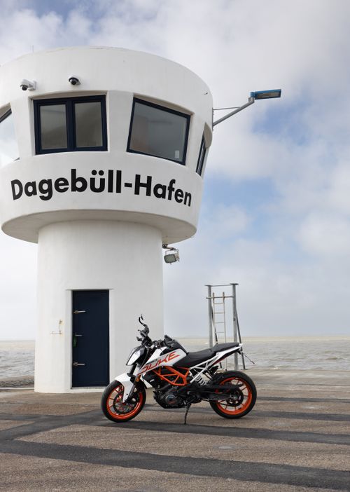 Free Motorcycle parked by the Dagebüll Hafen tower in Schleswig-Holstein, Germany. Stock Photo