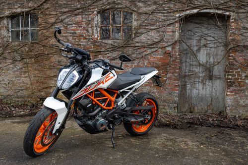 Free Orange and white motorcycle parked beside a rustic brick wall in Dagebüll, Germany. Stock Photo