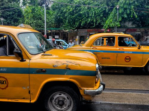 Free Classic yellow taxis navigate through the bustling streets of Kolkata, India. Stock Photo