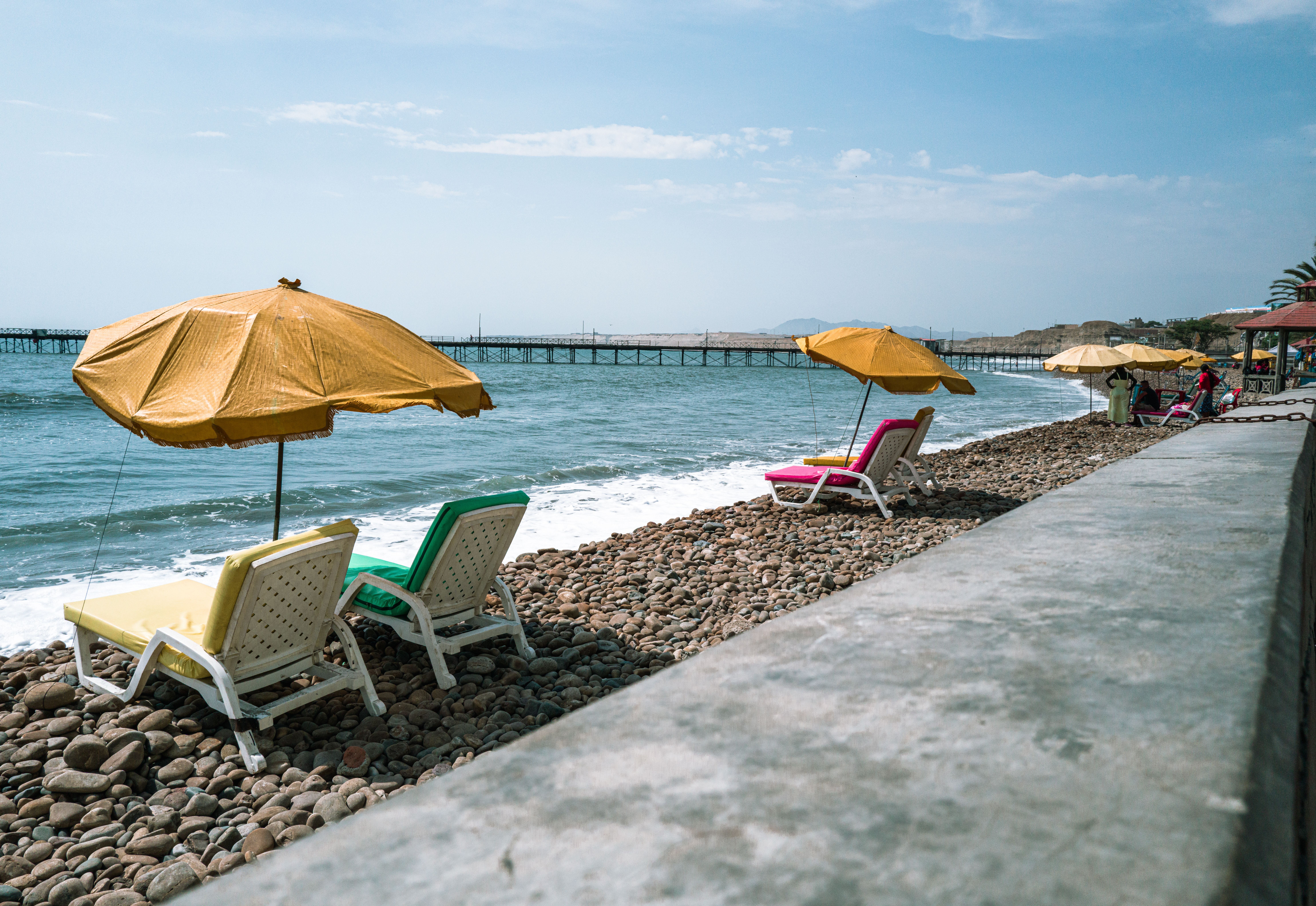 Relaxing view of colorful loungers and umbrellas on a pebble beach in Pacasmayo, Peru.