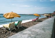 Relaxing view of colorful loungers and umbrellas on a pebble beach in Pacasmayo, Peru.