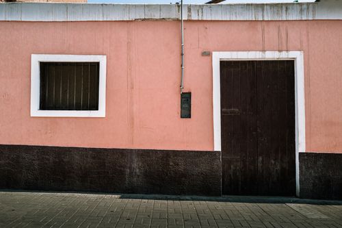 Free Street scene featuring a traditional pink facade with window and door in Pacasmayo, Peru. Stock Photo
