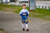 小男孩穿着运动服，拿着包走在户外的小路上