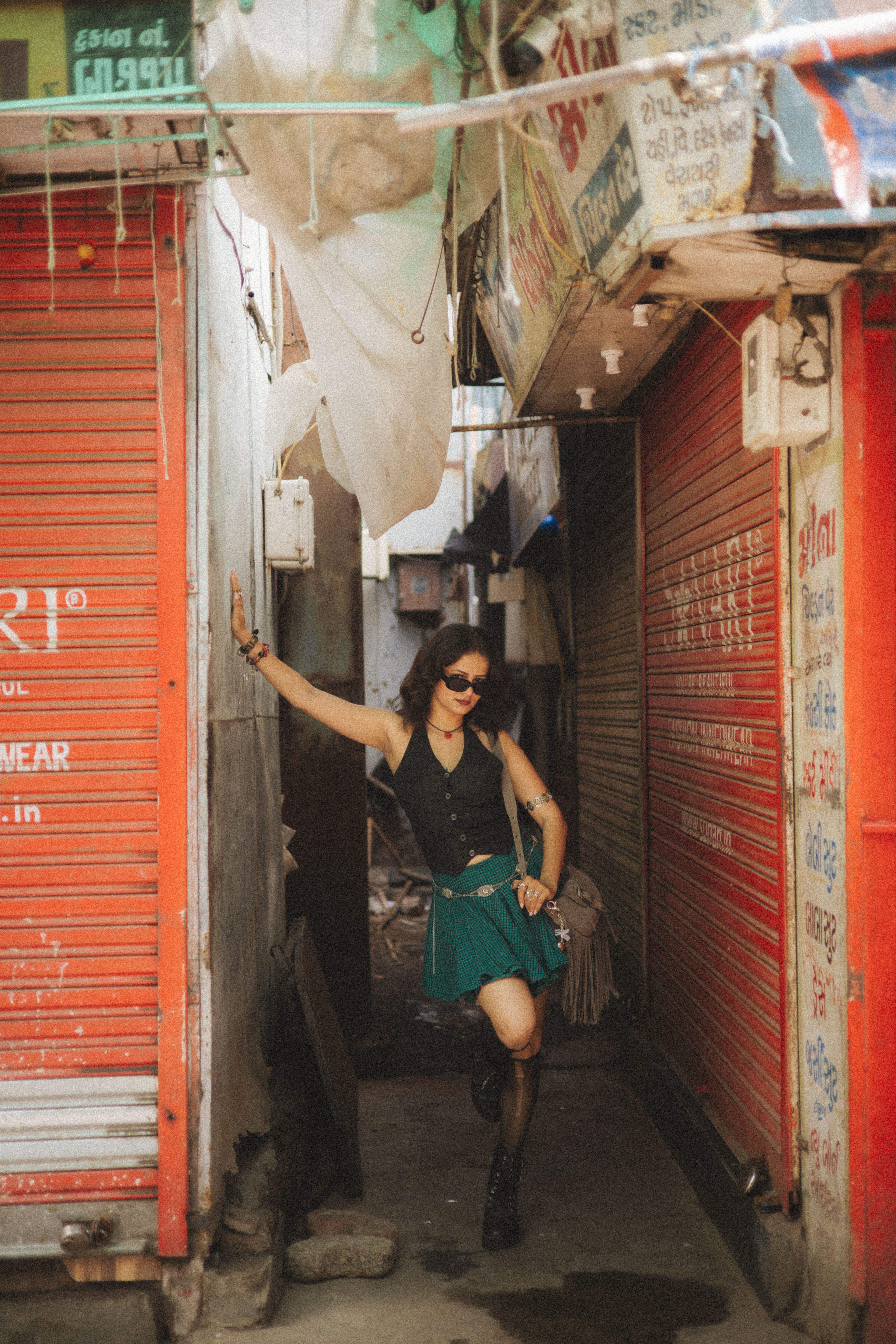 Stylish woman poses in a bustling alleyway with vibrant surroundings.
