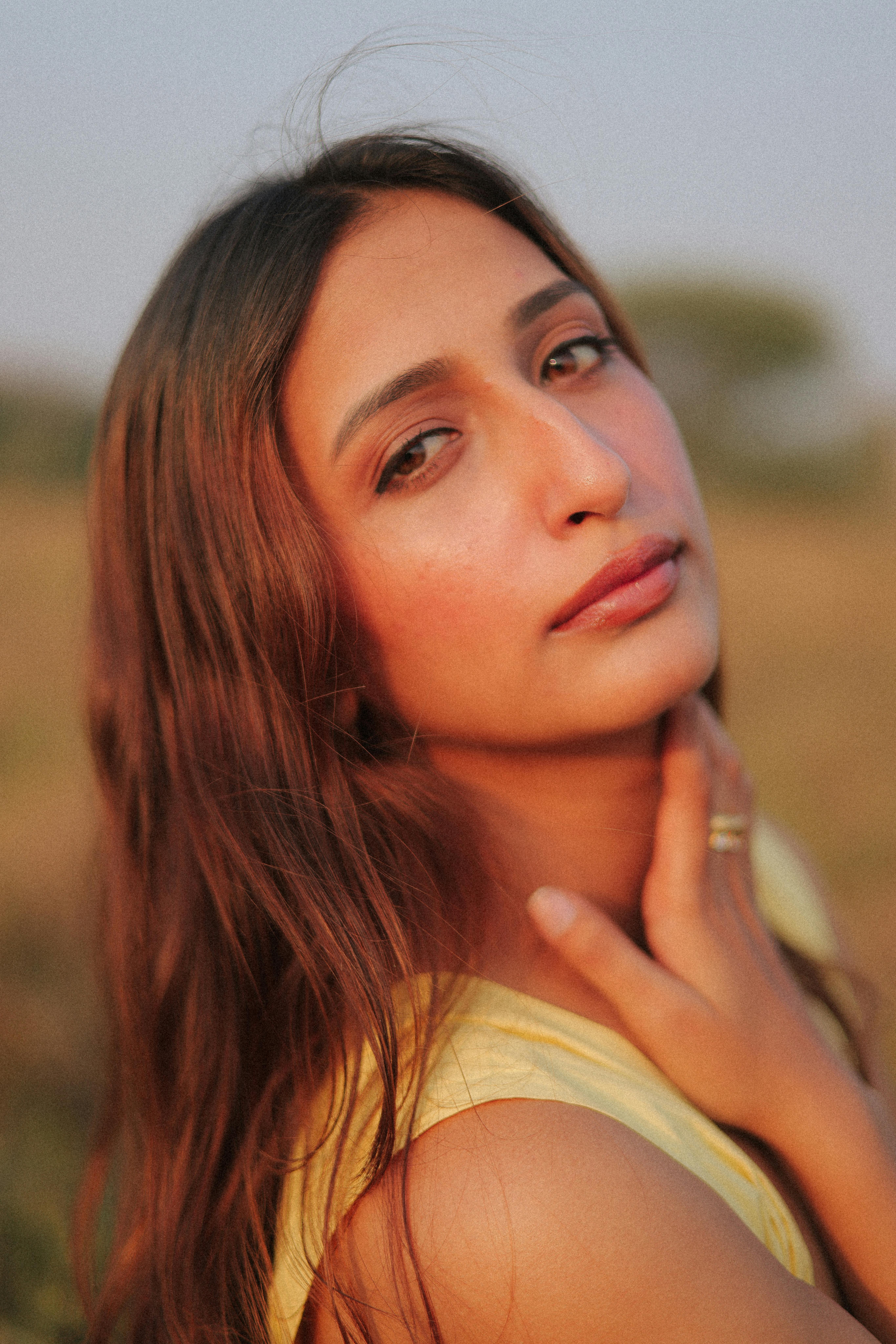 A serene portrait of a young woman with long hair in a natural outdoor setting.