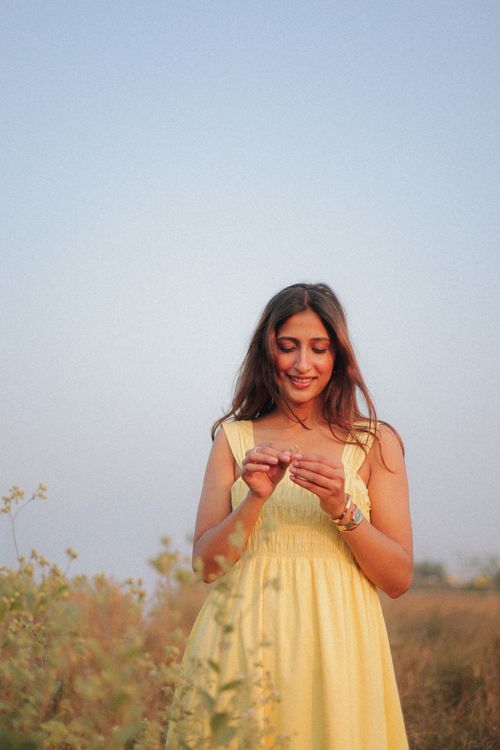 Free Smiling woman in yellow dress surrounded by nature, enjoying a sunny day outdoors. Stock Photo