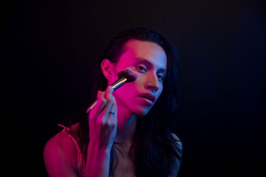 A captivating portrait of a person using a makeup brush under vibrant lighting.