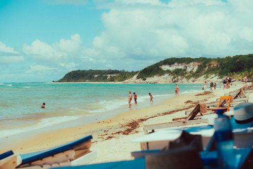Free A vibrant beach scene with people enjoying a sunny day at the shore, blue skies, and gentle waves. Stock Photo