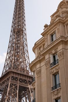 Elegant view of the Eiffel Tower next to classic Parisian buildings under a clear sky.