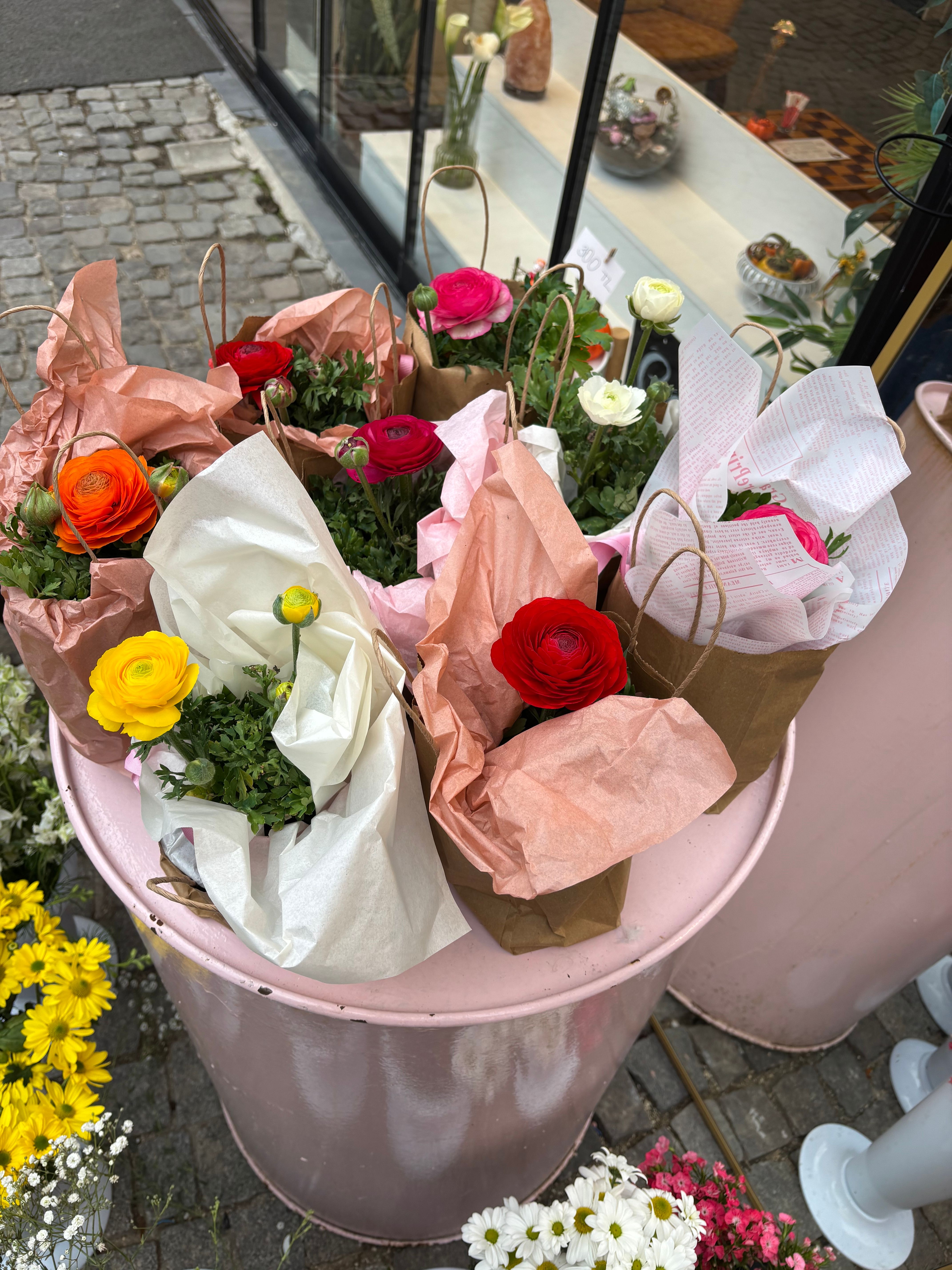 Gratis Livlige blomster pakket ind i papirsposer udstillet på en rustik tønde udendørs. Lagerfoto