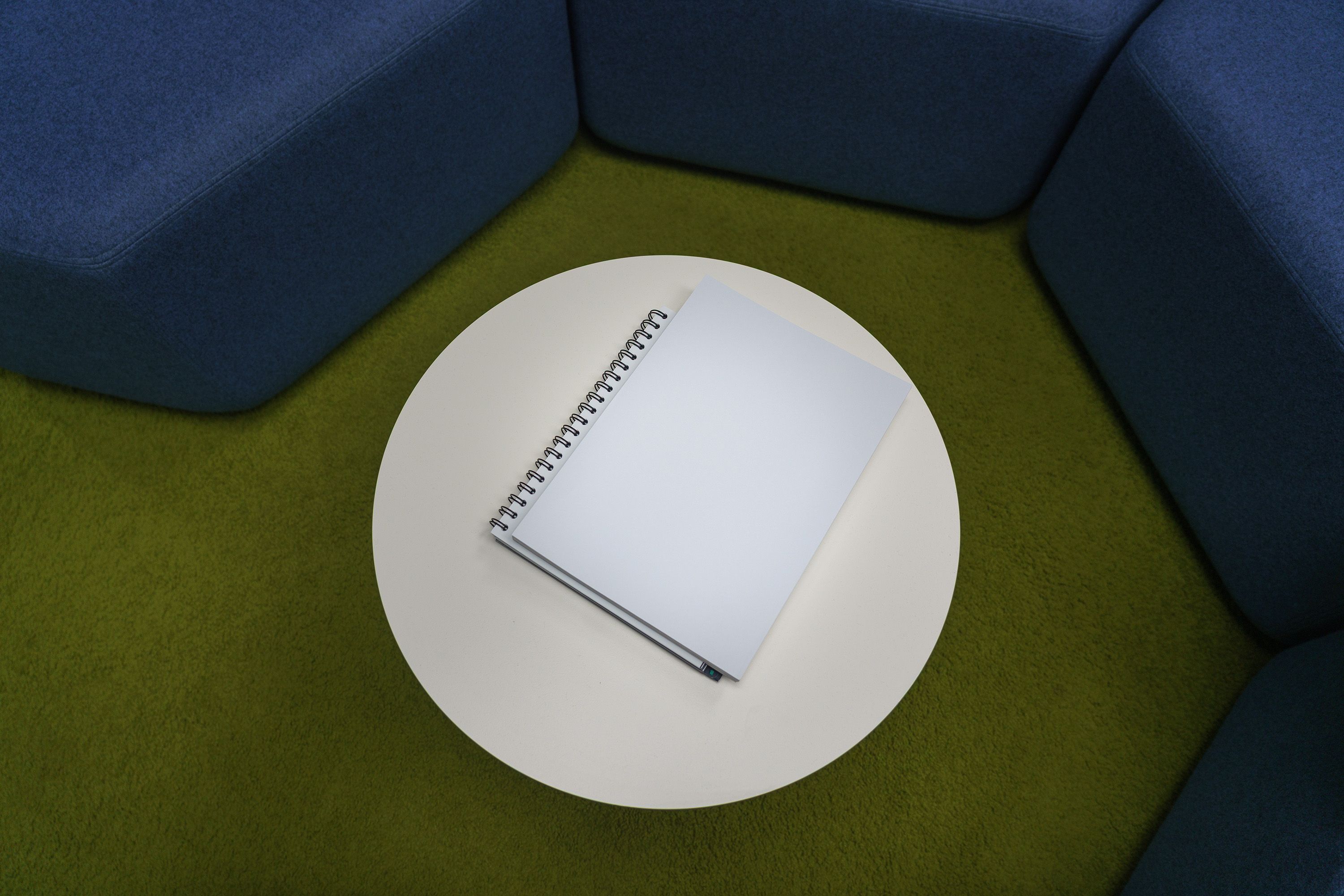 Spiral notepad on a round table in a modern lounge setting, providing ample copyspace.