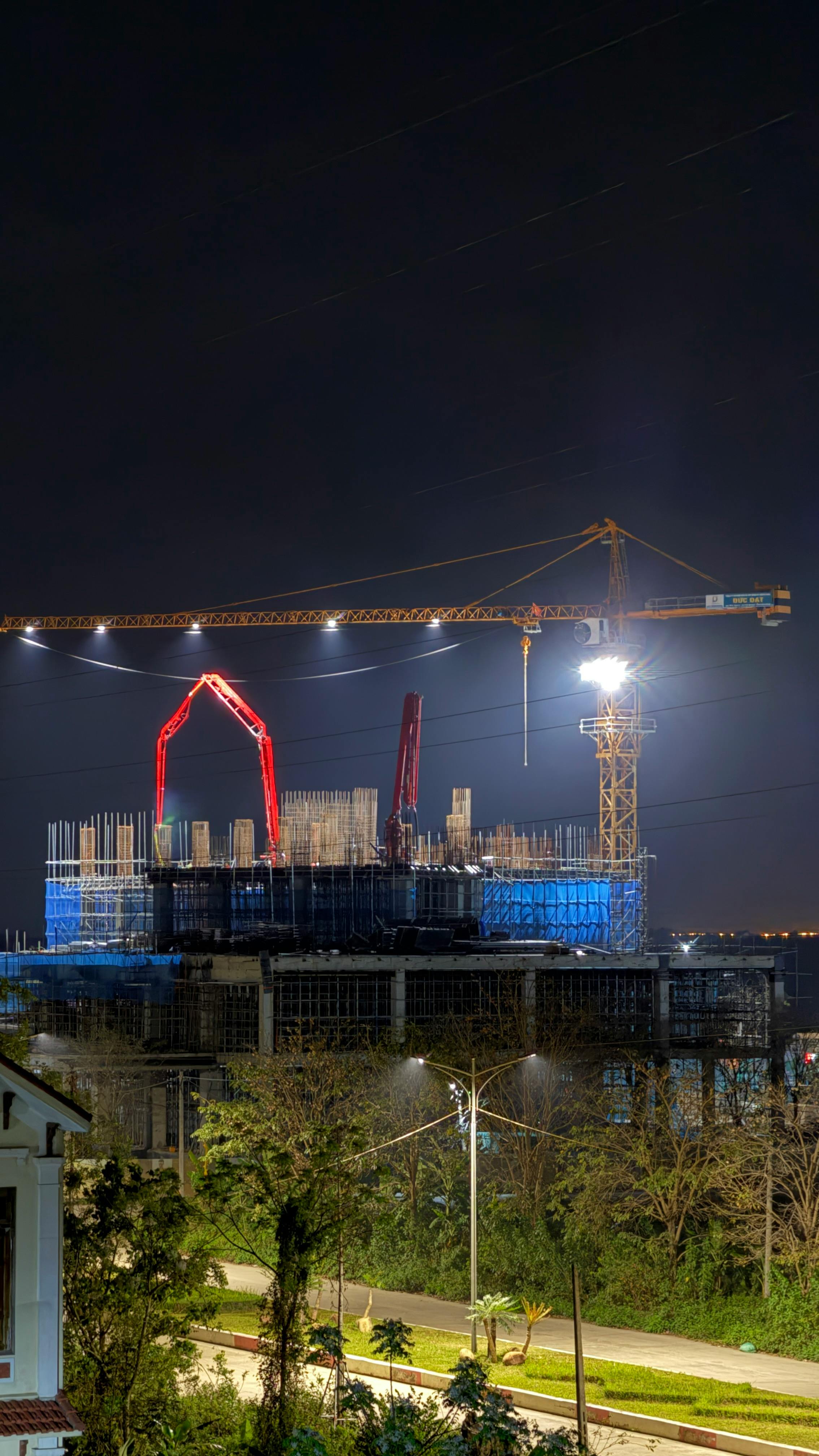 Urban construction site at night with cranes and bright lights, showcasing city development.