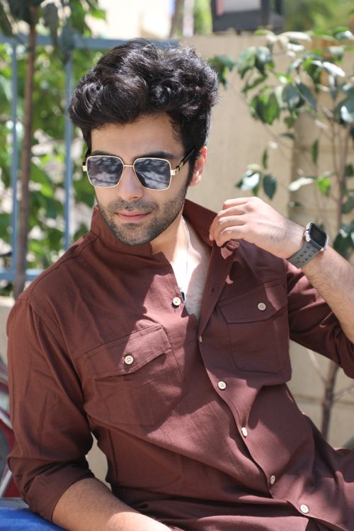 Free Confident man wearing sunglasses and a brown shirt enjoying the sunny day. Stock Photo
