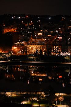 Dramatic night view of a city's illuminated buildings reflecting in a river.
