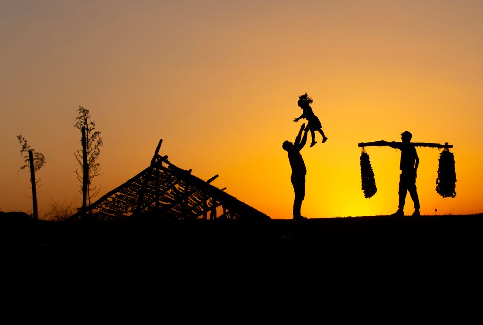 Silhouette of a family enjoying a sunset, with vibrant orange sky backdrop.