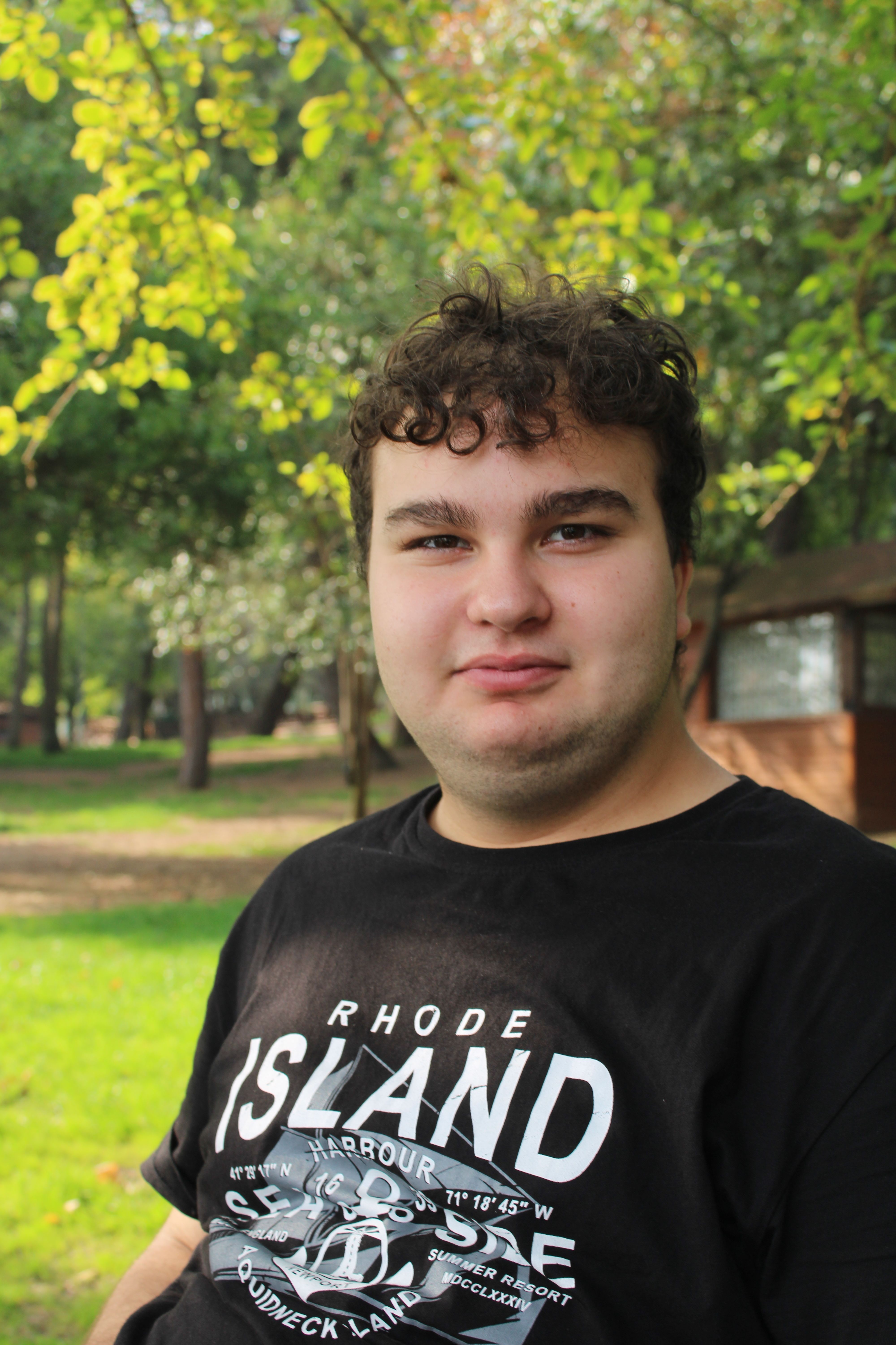 Portrait of a young man enjoying a sunny day outdoors in a green park setting.