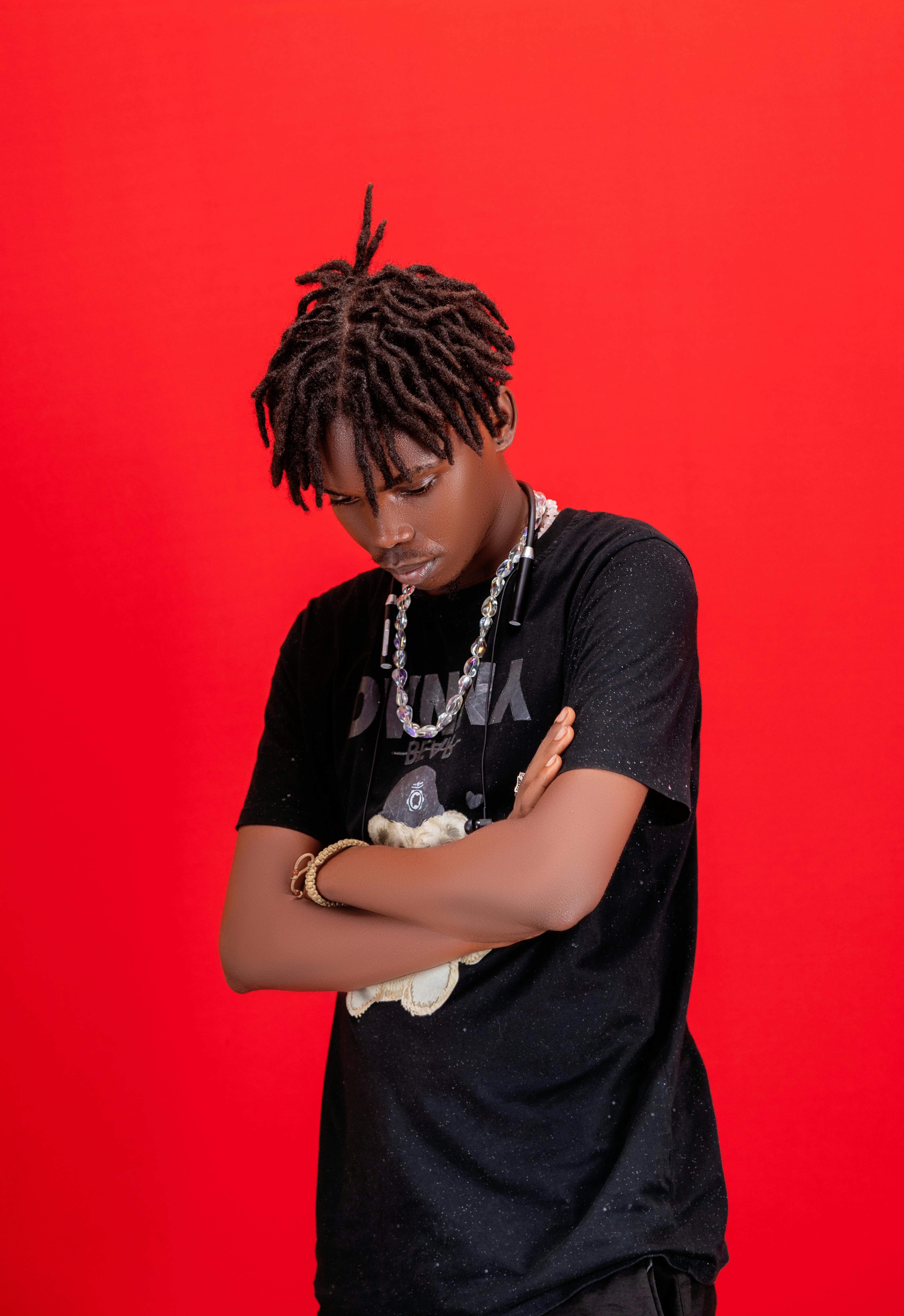 Portrait of a stylish young man with a red background, wearing a black t-shirt.