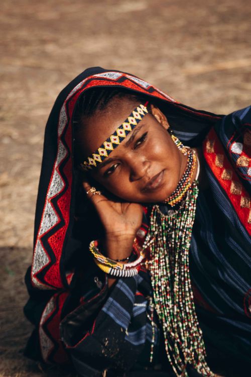 Free A woman in colorful traditional African attire and jewelry against an outdoor backdrop. Stock Photo