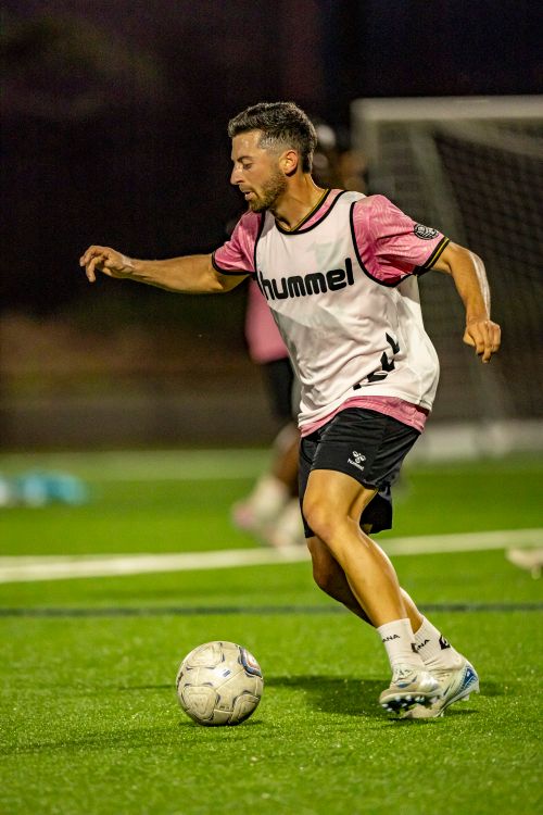 Free A focused soccer player practicing on a well-lit field during a night training session. Stock Photo