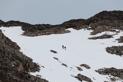 Two hikers ascending a snowy mountain slope in Patagonia, Chile, showcasing adventure and nature.
