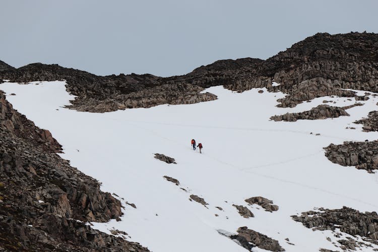 People Walking On Snow Capped  Mountain