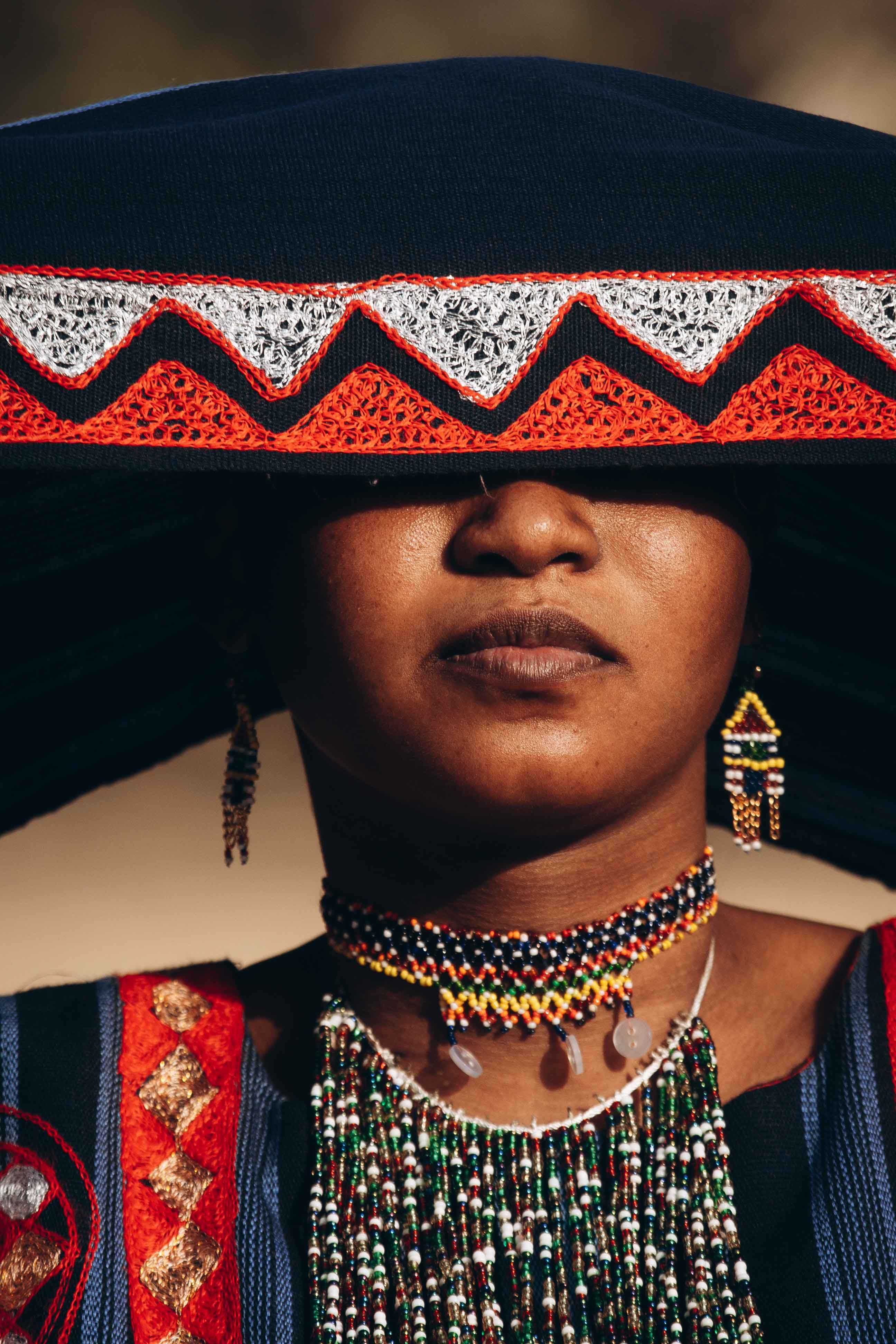 Close-up of a woman in traditional African attire with vibrant embroidery and beadwork jewelry.