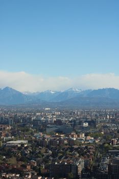 Aerial view of Milan showcasing urban landscape with distant Alps on a clear day.