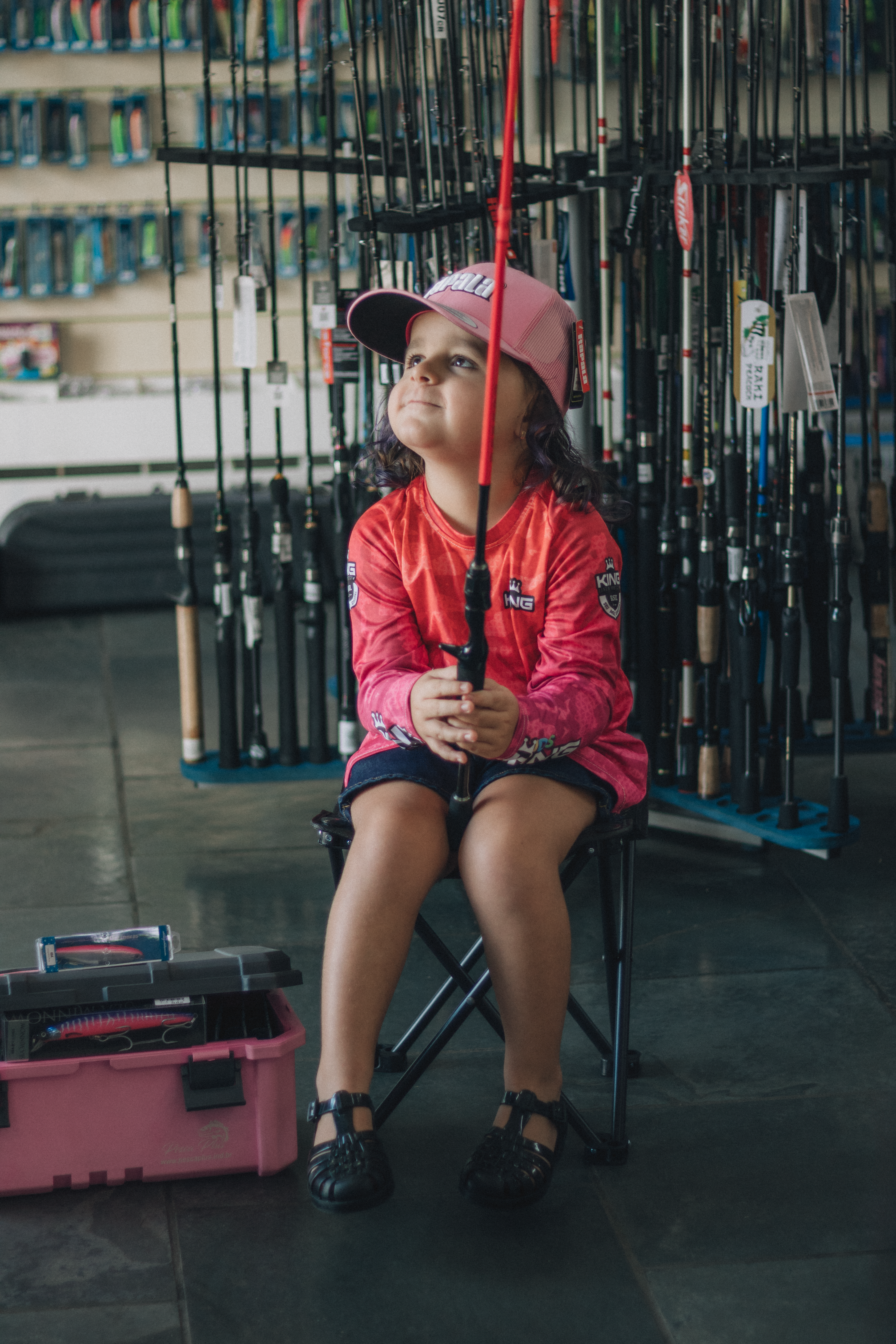 Young girl in fishing store, exploring equipment with enthusiasm.