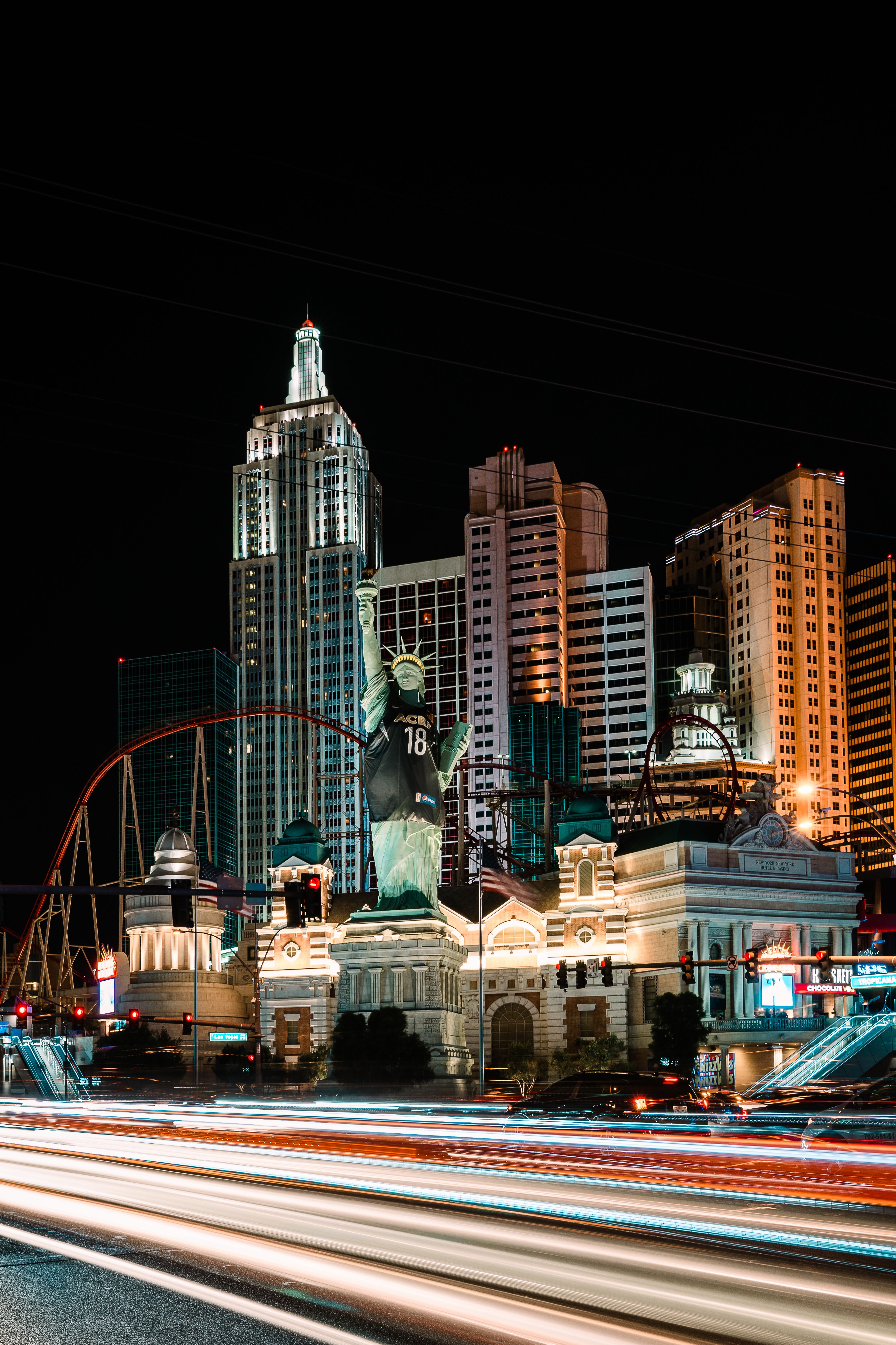 Long exposure night shot of Las Vegas's Statue of Liberty with city lights and modern architecture.