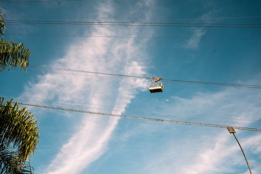 Cable car suspended in the sky with palm trees and streetlights in Rio de Janeiro, Brazil.