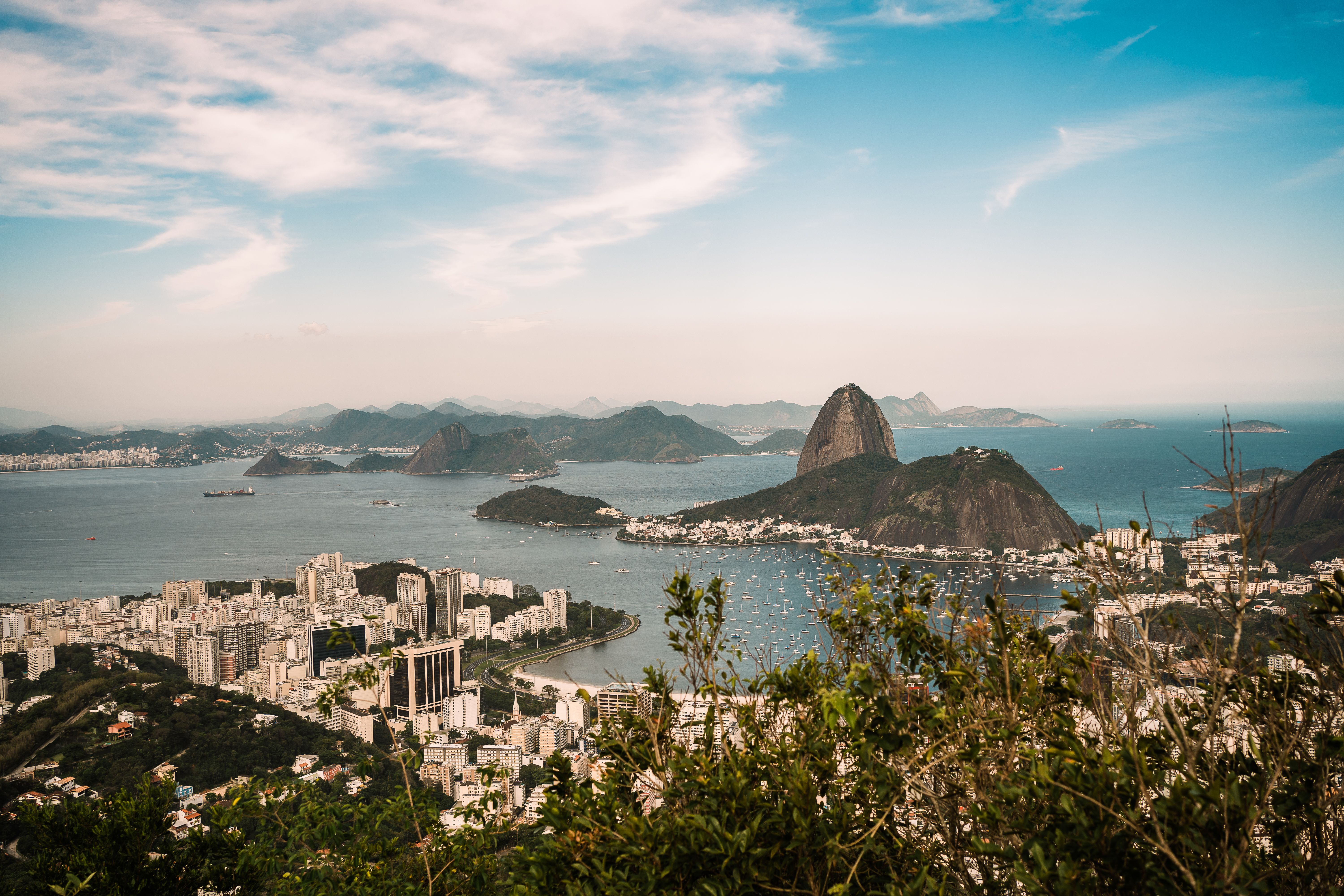 Aerial panorama of Rio de Janeiro with Sugarloaf Mountain, city skyline, and blue Atlantic water.