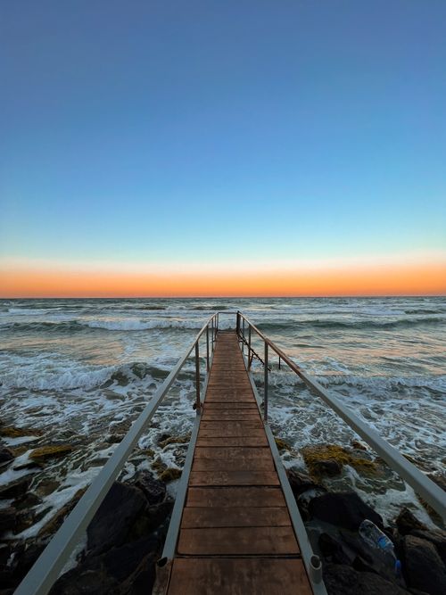 Free A breathtaking sunset viewed from a pier in Tekirdağ, Türkiye, with vivid ocean waves and orange skies. Stock Photo