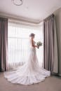美丽的新娘穿着白色婚纱，在室内窗前摆姿势