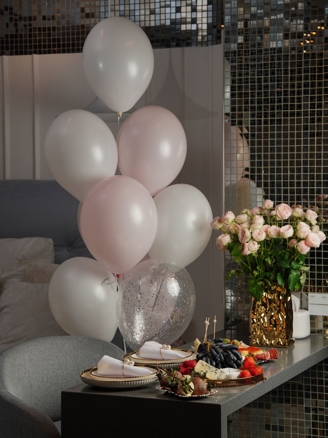 Elegant celebration table with balloons, roses, fruit, and refined event styling