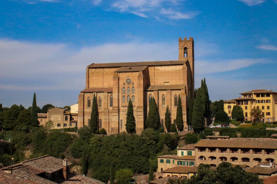 Scenic view of Basilica of San Domenico surrounded by lush greenery in Siena, Italy.