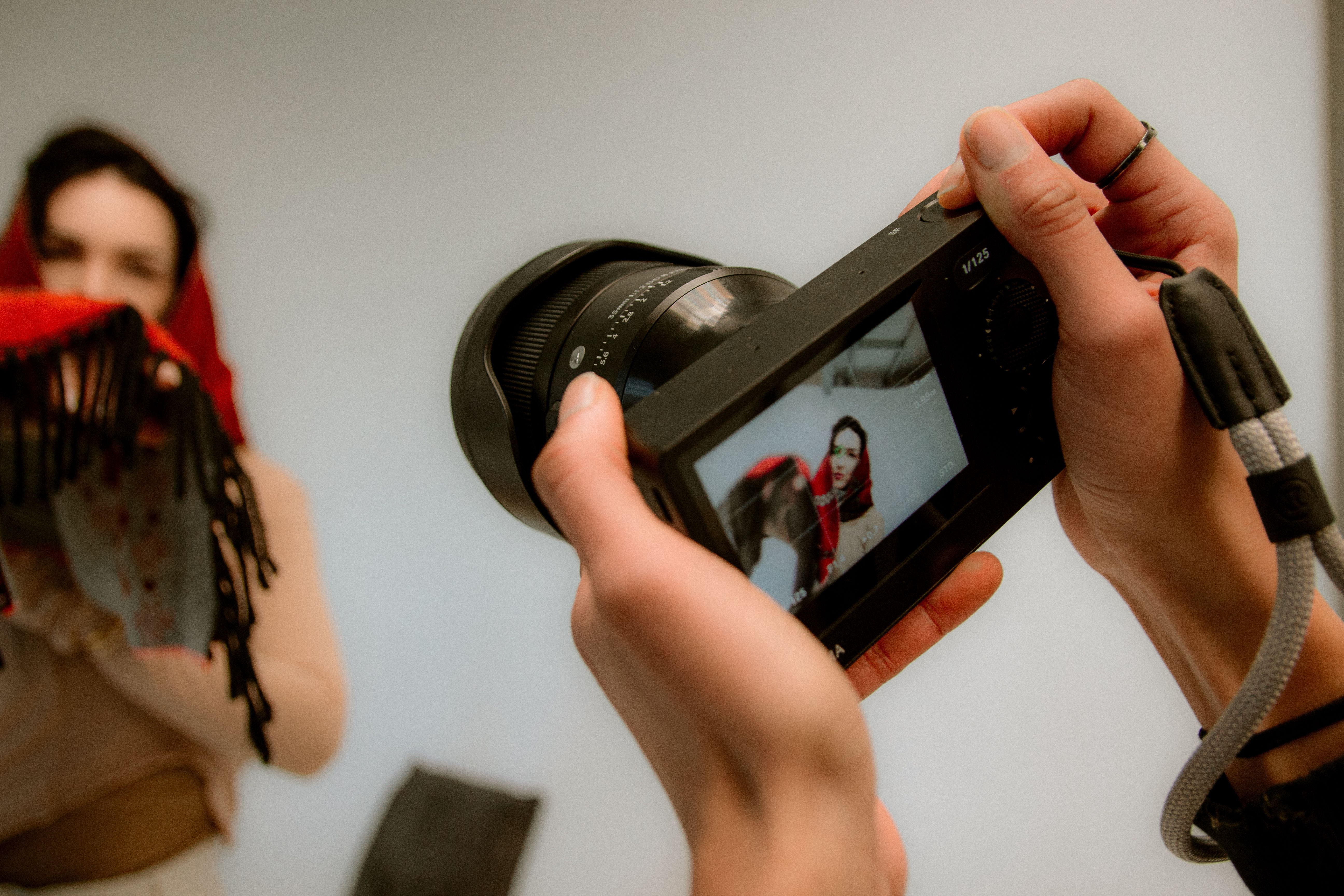 Close-up of a camera displaying a person in a red shawl during a photoshoot.