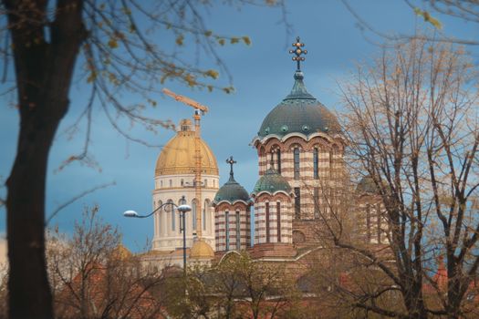 Scenic view of elegant church domes in Bucharest, surrounded by trees under a clear sky.