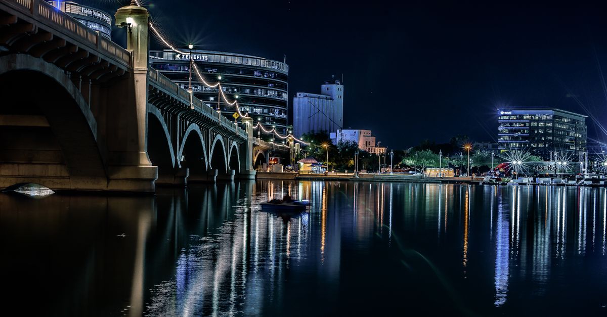 Stunning night view of Tempe, Arizona, featuring the illuminated bridge and skyline reflections on the water.