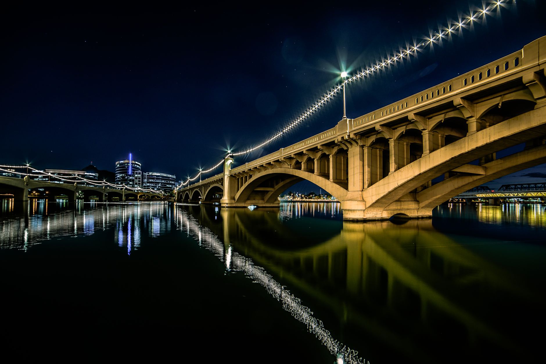 Stunning night view of the illuminated bridge at Tempe Town Lake, Arizona, reflecting in the water.