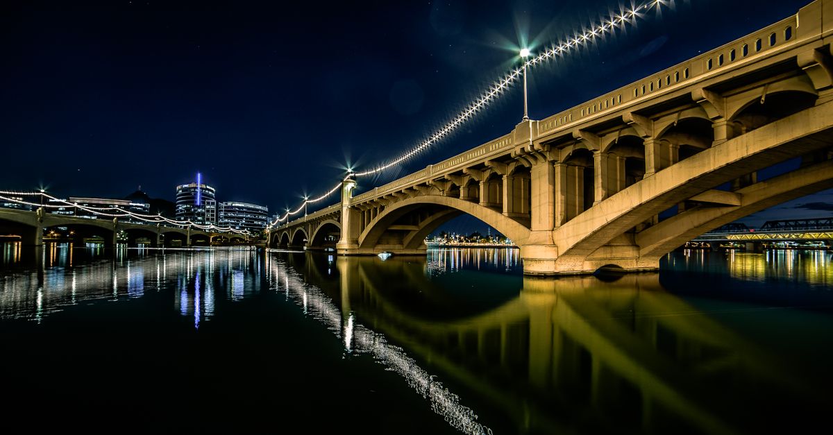 Stunning night view of the illuminated bridge at Tempe Town Lake, Arizona, reflecting in the water.